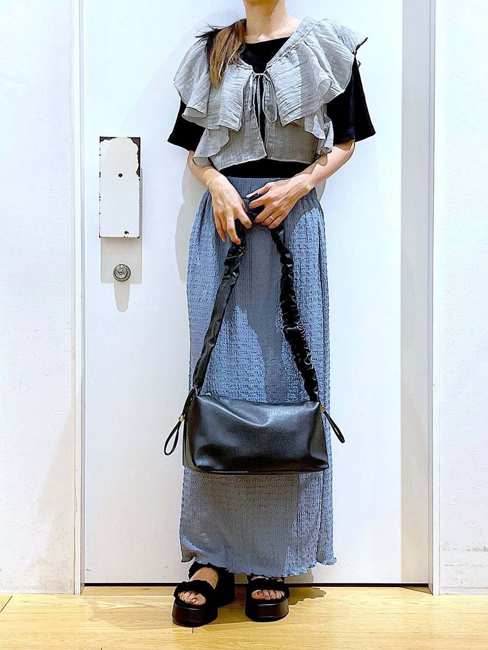 ブラック系のショルダーバッグ、ブルー系のスカート、ブラック系のTシャツ/カットソーを着用したレディースの夏コーディネートの6枚目の写真