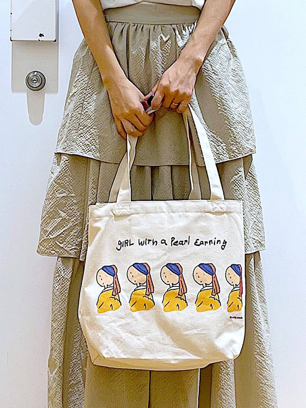 ベージュ系のスカート、ホワイト系のTシャツ/カットソー、その他のトートバッグを着用したレディースの春コーディネートの9枚目の写真