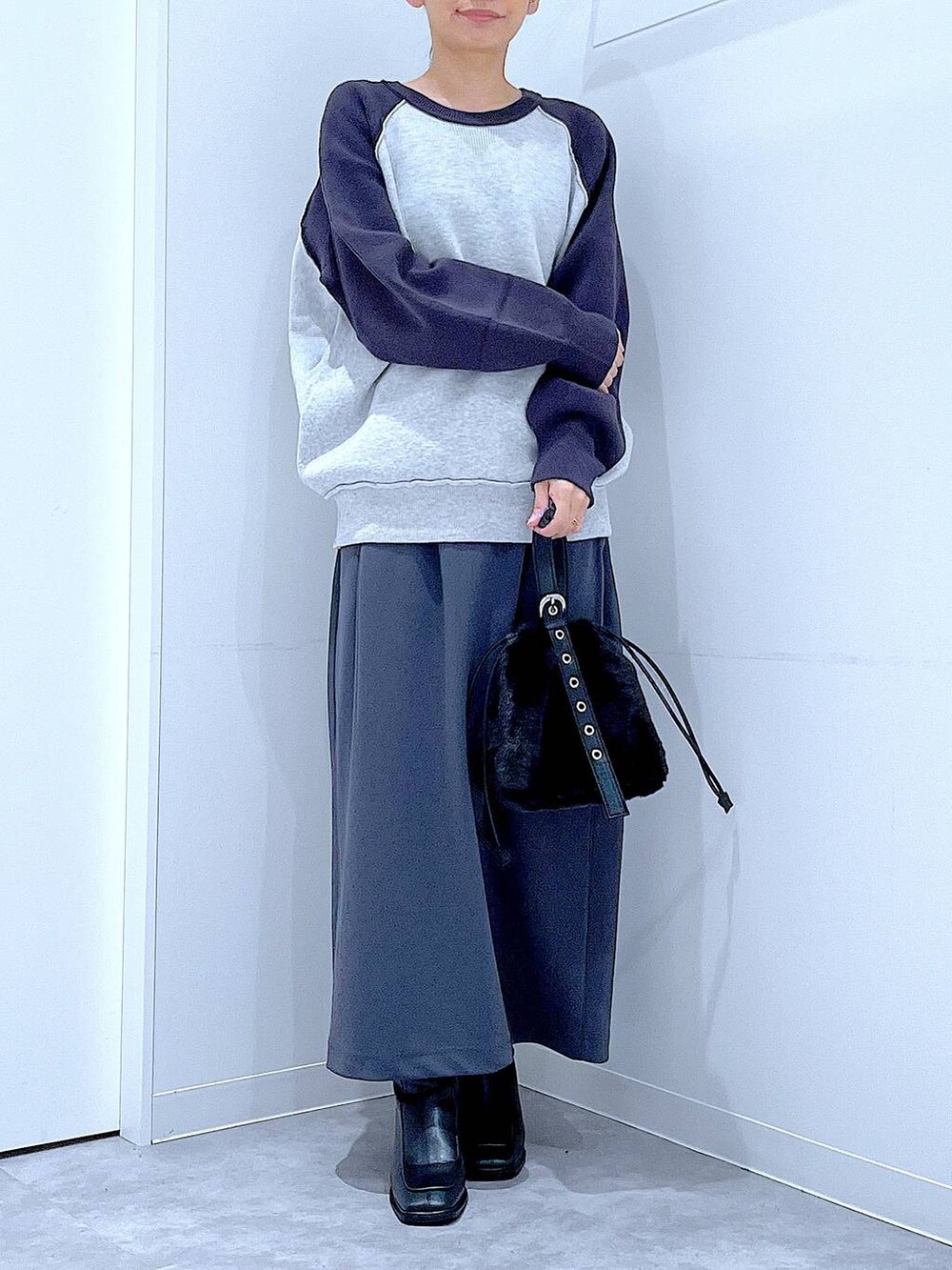 グレー系のスカート、グレー系のニット/セーター、ブラック系のブーツを着用したレディースの秋コーディネートの6枚目の写真