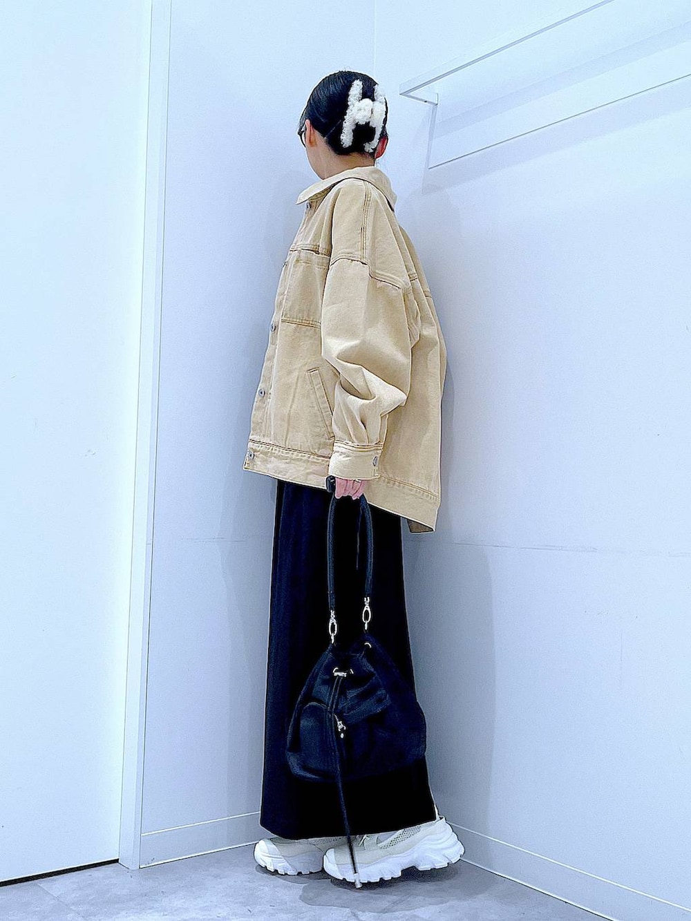 ブラック系のスカート、ベージュ系のデニムジャケット、ブラック系のショルダーバッグを着用したレディースの春コーディネートの3枚目の写真