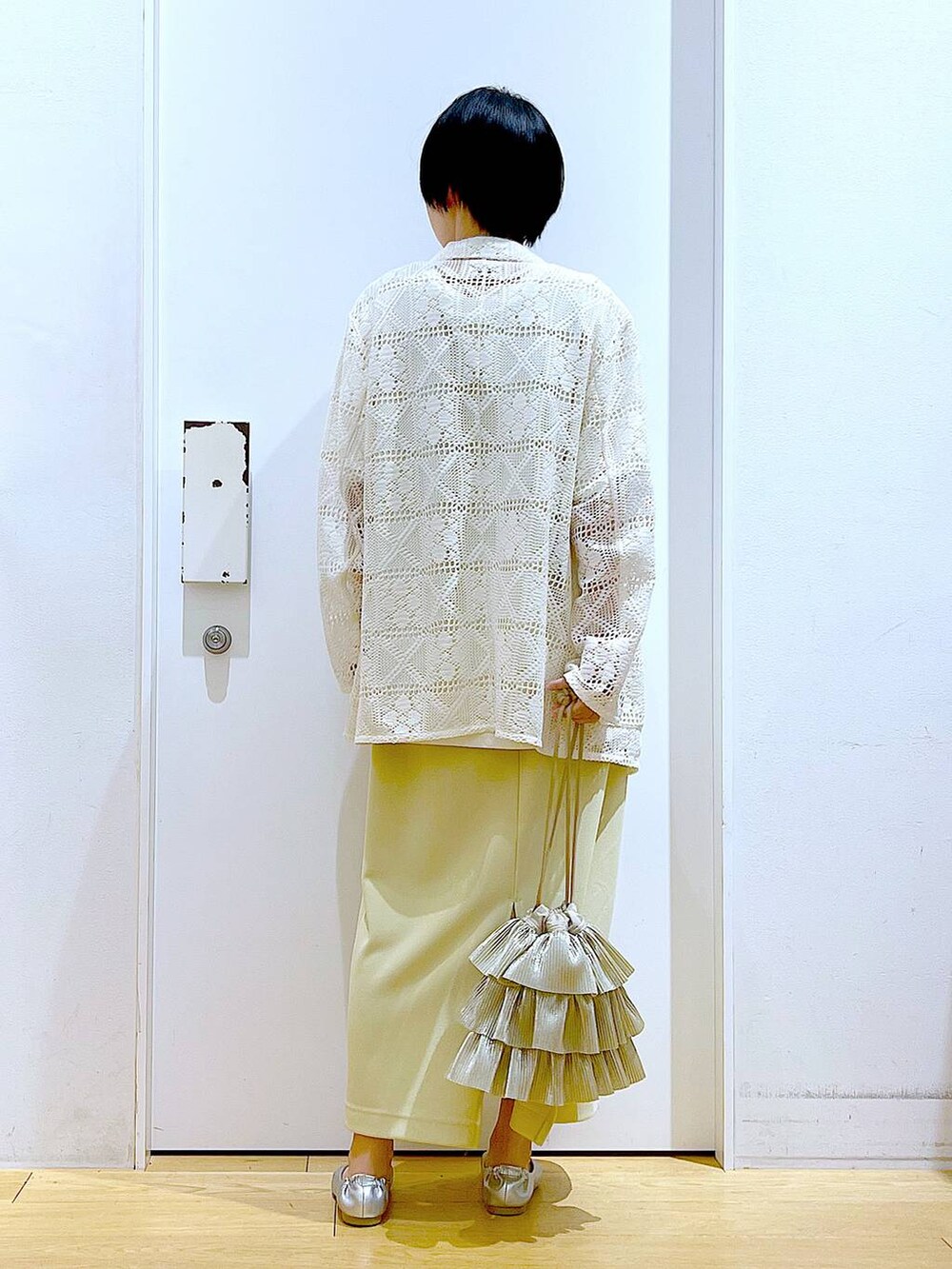 シルバー系のパンプス、ベージュ系のショルダーバッグ、イエロー系のスカートを着用したレディースの春コーディネートの5枚目の写真