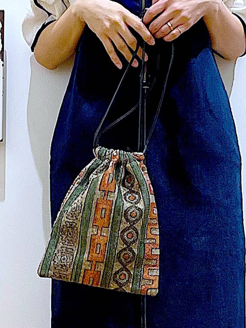 ブルー系のジャンパースカート、ブラウン系のショルダーバッグ、ブラック系のサンダルを着用したレディースの夏コーディネートの9枚目の写真