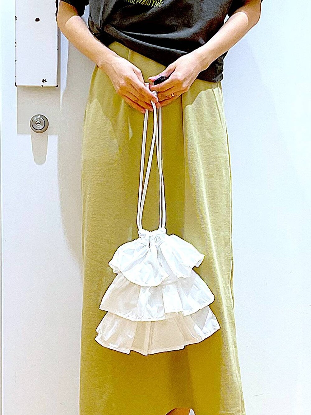 ホワイト系のショルダーバッグ、イエロー系のワンピース、ホワイト系のパンプスを着用したレディースの春コーディネートの9枚目の写真