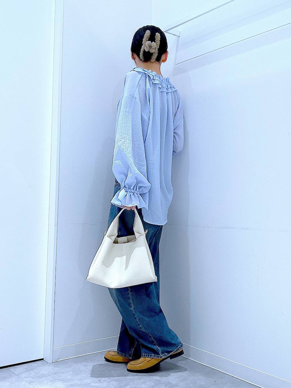 ブルー系のデニムパンツ、ベージュ系のローファー、ホワイト系のトートバッグを着用したレディースの春コーディネートの3枚目の写真