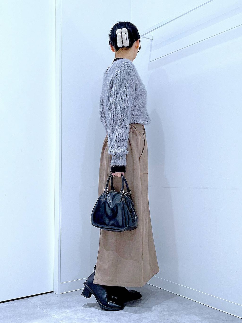 ブラック系のブーツ、ブラック系のショルダーバッグ、ブラウン系のスカートを着用したレディースの冬コーディネートの4枚目の写真