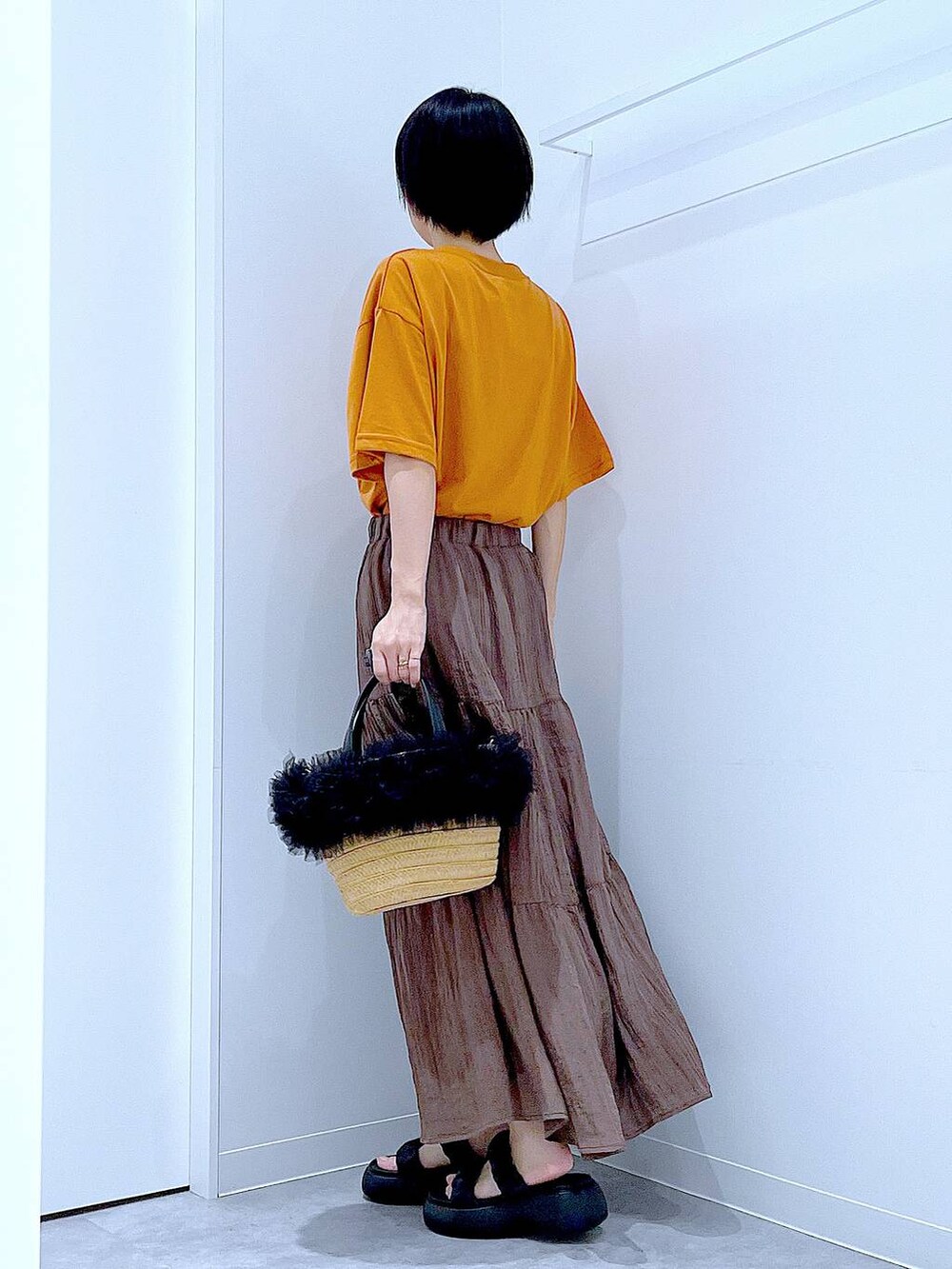 ベージュ系のショルダーバッグ、ブラック系のサンダル、オレンジ系のTシャツ/カットソーを着用したレディースの夏コーディネートの3枚目の写真