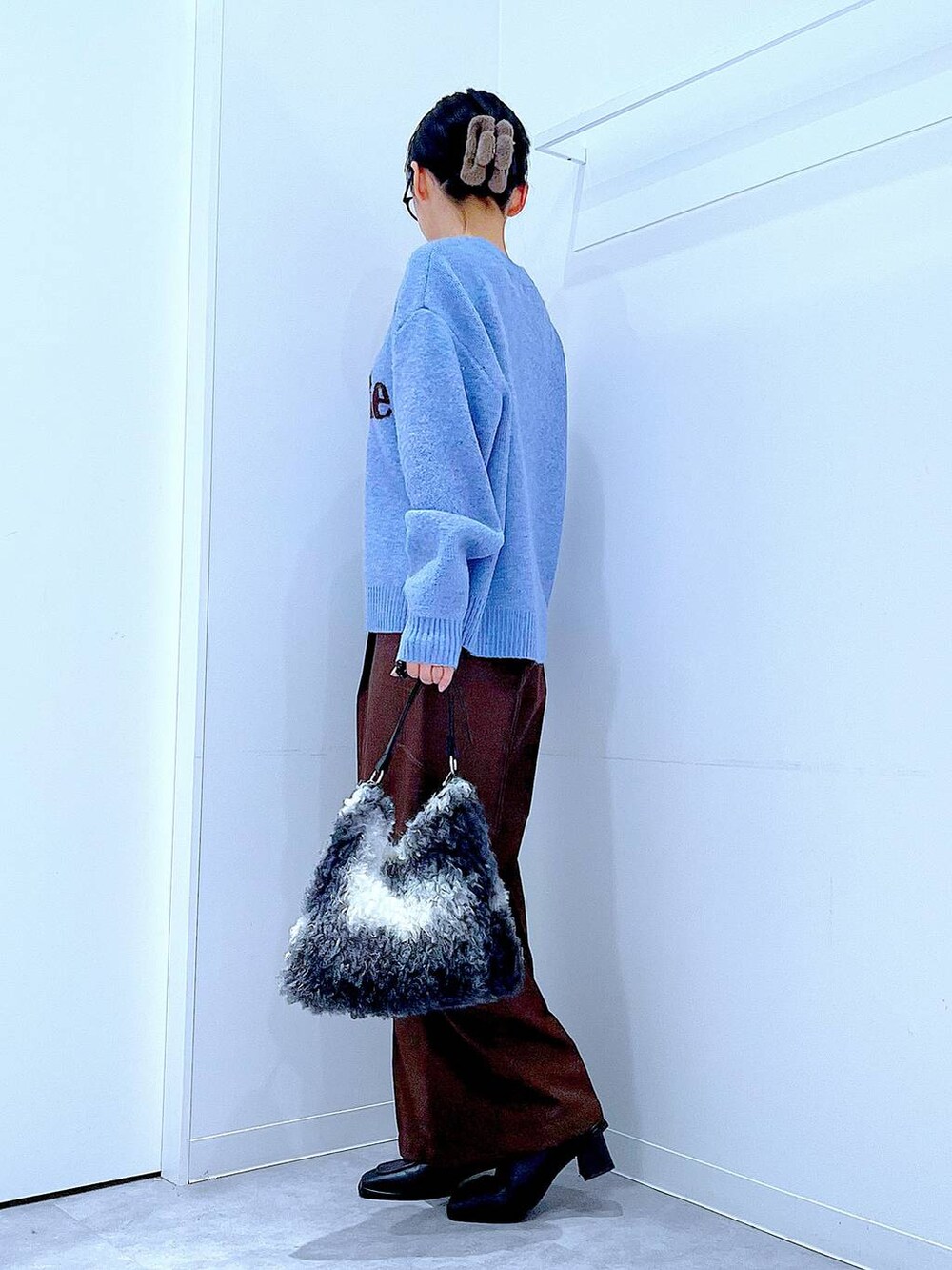 ブラック系のブーツ、ブラウン系のスラックス、ブラック系のショルダーバッグを着用したレディースの冬コーディネートの3枚目の写真