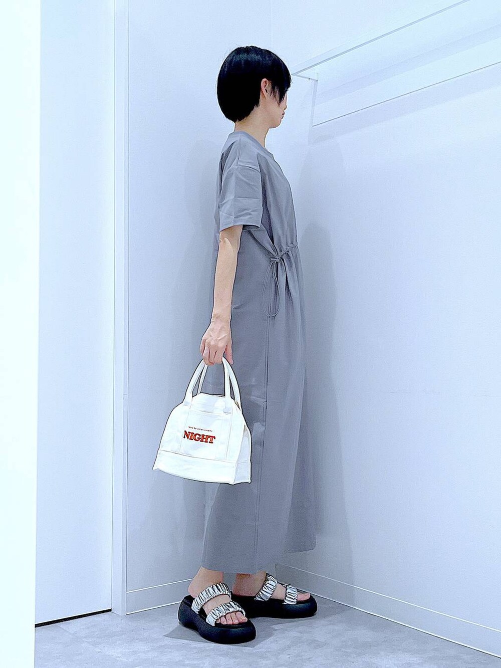 シルバー系のサンダル、グレー系のワンピース、ホワイト系のトートバッグを着用したレディースの夏コーディネートの4枚目の写真