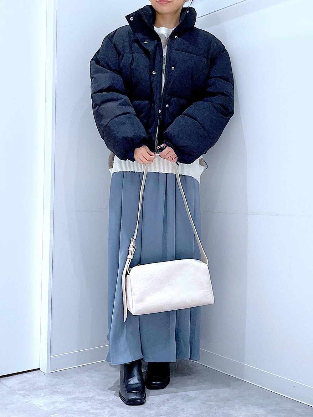 ブラック系のブルゾン、ブラック系のブーツ、ベージュ系のニット/セーターを着用したレディースの冬コーディネートの6枚目の写真