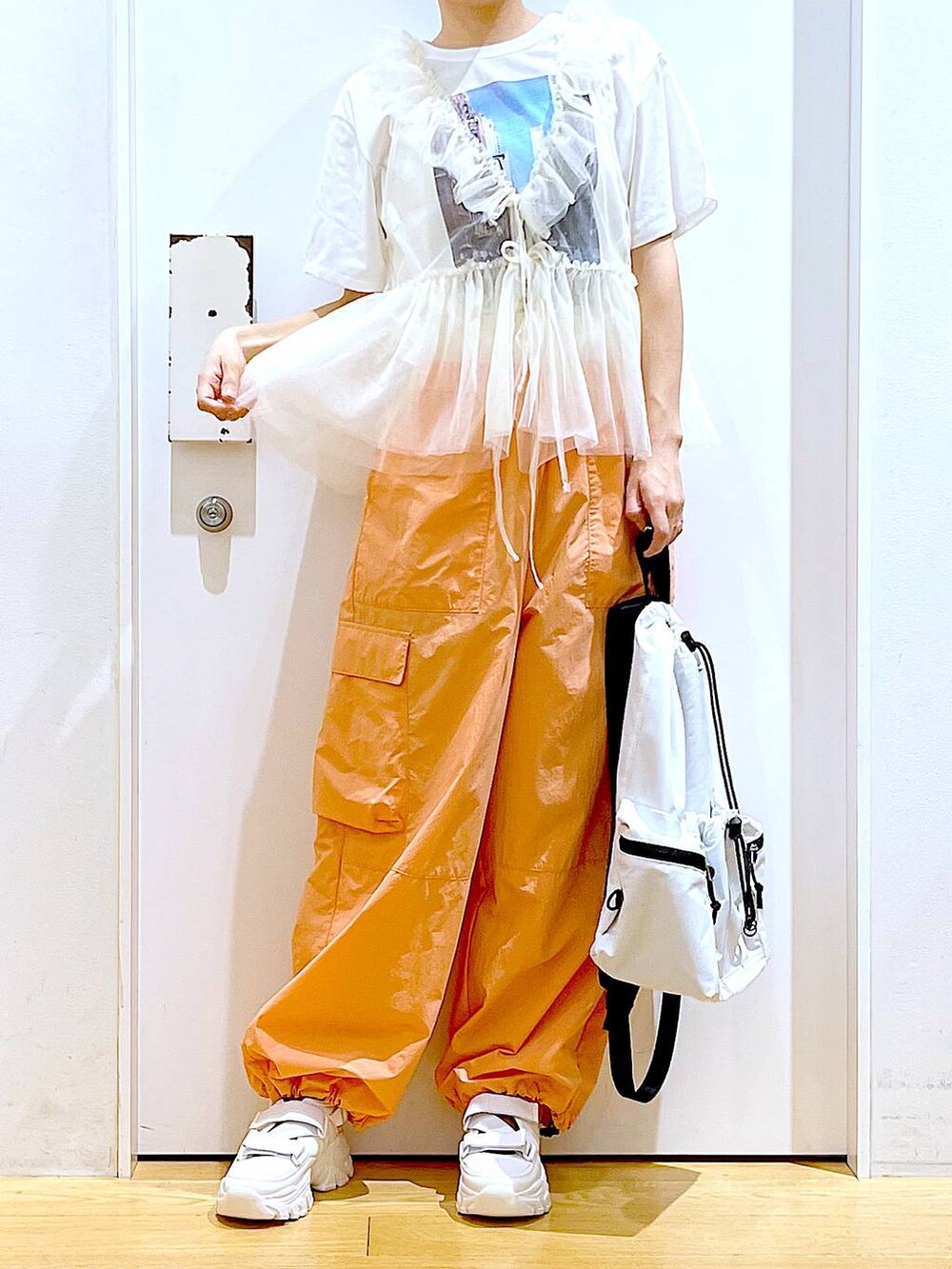 ホワイト系のスニーカー、ホワイト系のショルダーバッグ、オレンジ系のカーゴパンツを着用したレディースの夏コーディネートの7枚目の写真