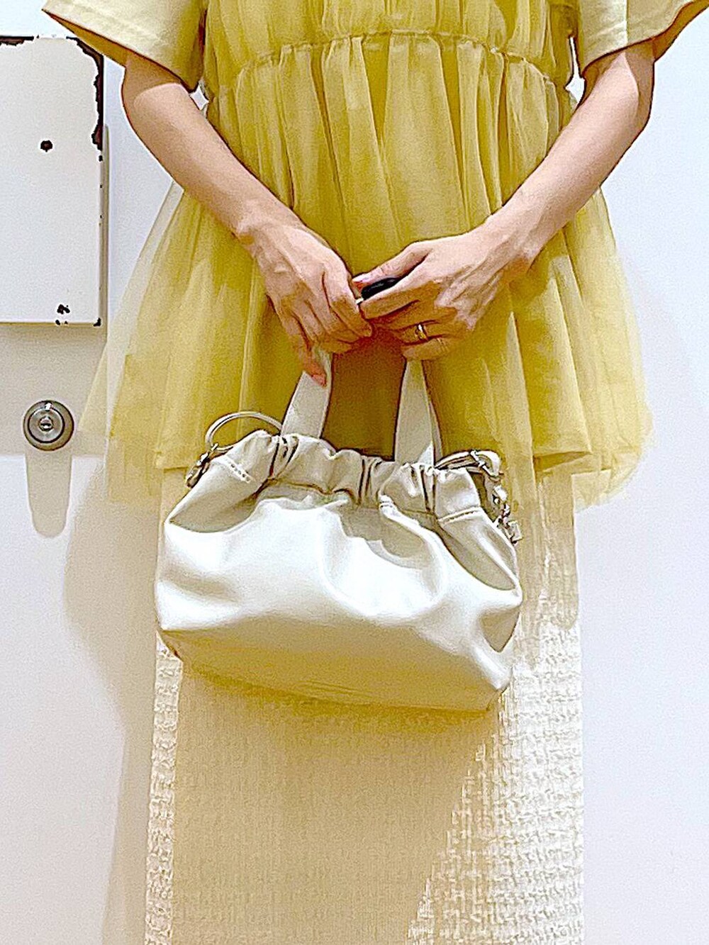 ホワイト系のサンダル、ベージュ系のスカート、イエロー系のTシャツ/カットソーを着用したレディースの夏コーディネートの9枚目の写真