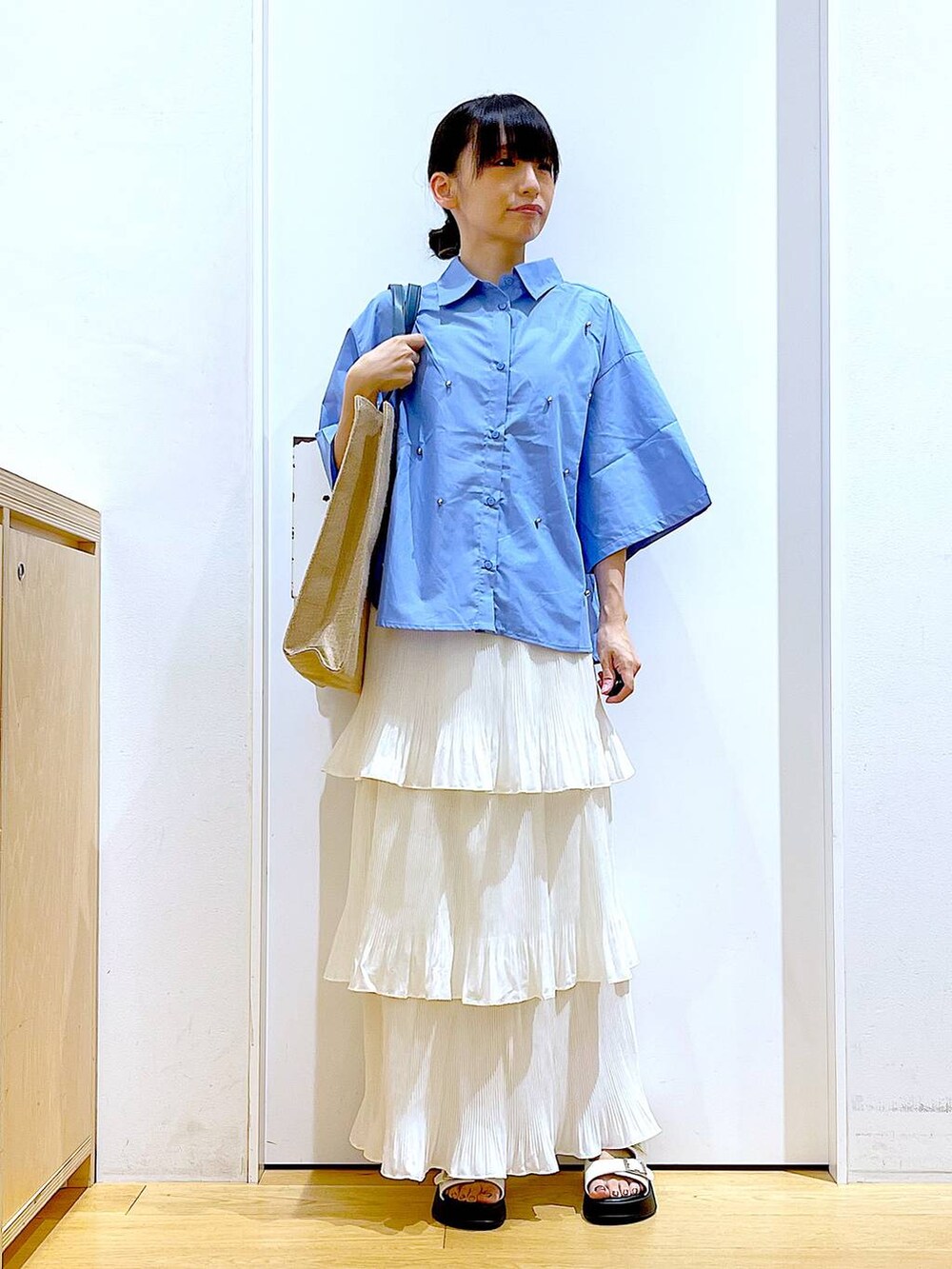 ベージュ系のスカート、ブルー系のトートバッグ、ホワイト系のサンダルを着用したレディースの夏コーディネートの2枚目の写真