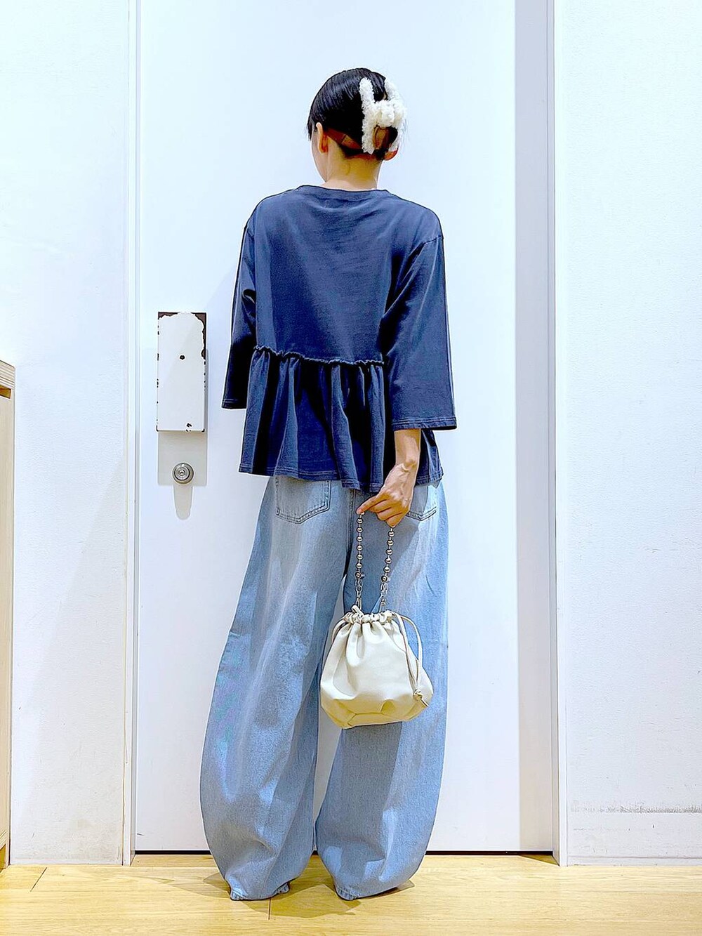 ブラック系のショルダーバッグ、ブルー系のデニムパンツ、シルバー系のパンプスを着用したレディースの秋コーディネートの5枚目の写真