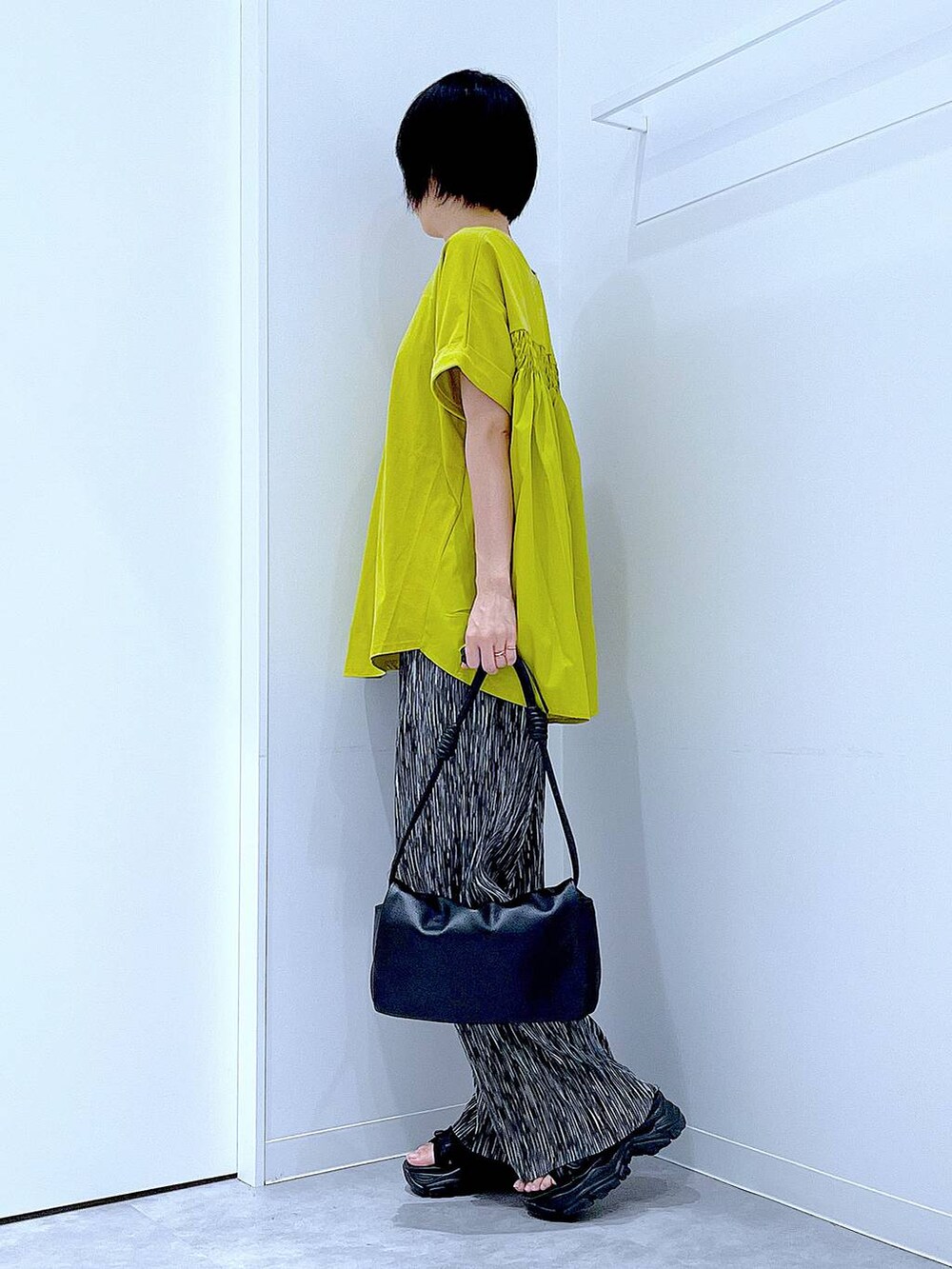 ブラック系のスニーカー、ブラック系のショルダーバッグ、グリーン系のTシャツ/カットソーを着用したレディースの夏コーディネートの3枚目の写真