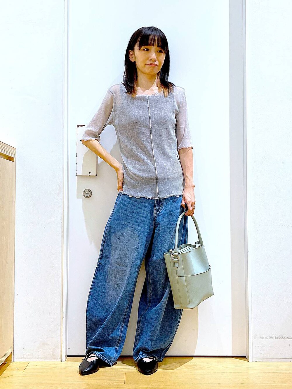 グレー系のTシャツ/カットソー、ブルー系のデニムパンツ、グリーン系のショルダーバッグを着用したレディースの秋コーディネートの2枚目の写真