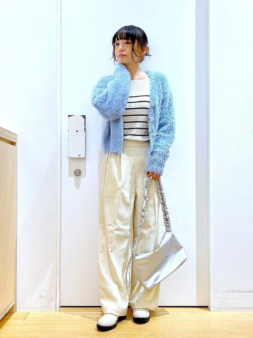 シルバー系のショルダーバッグ、ベージュ系のブーツ、ホワイト系のニット/セーターを着用したレディースの冬コーディネートの2枚目の写真