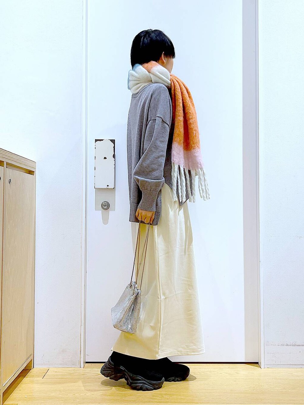 ブラック系のブーツ、ホワイト系のスカート、グレー系のニット/セーターを着用したレディースの冬コーディネートの4枚目の写真