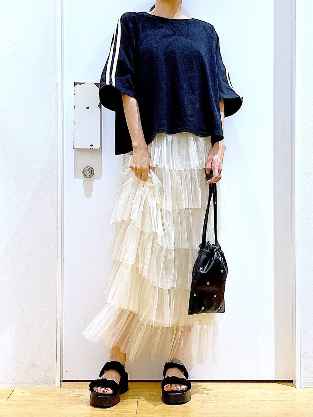 ブラック系のサンダル、ブラック系のショルダーバッグ、ベージュ系のスカートを着用したレディースの夏コーディネートの6枚目の写真