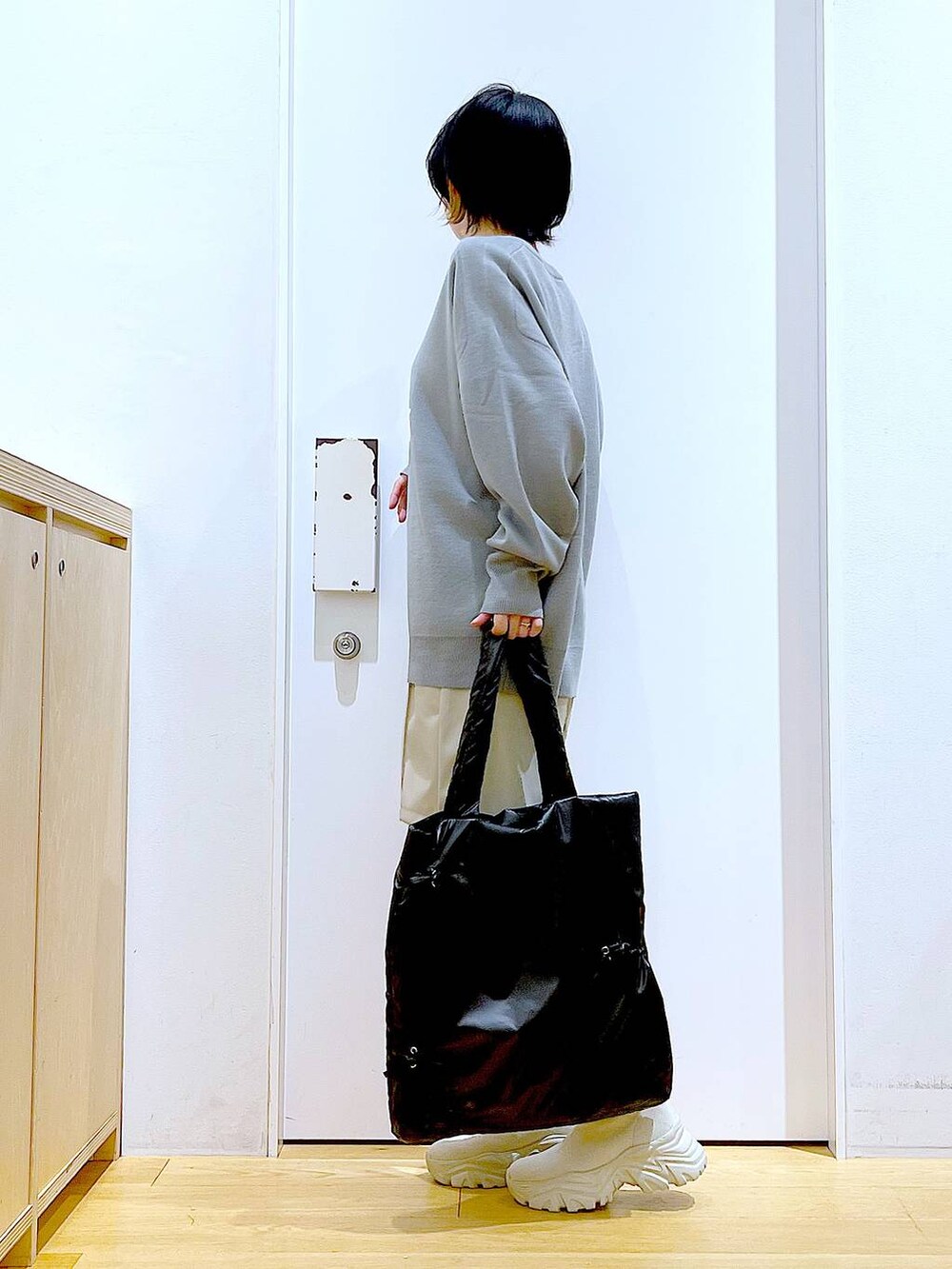 グレー系のニット/セーター、ブラック系のトートバッグ、ベージュ系のブーツを着用したレディースの冬コーディネートの3枚目の写真