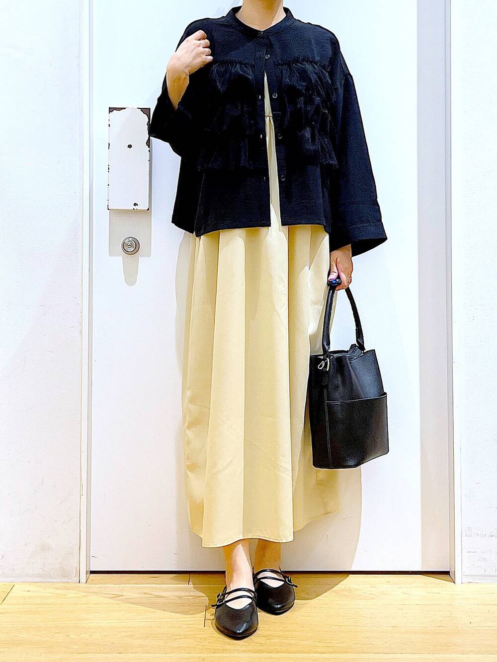 イエロー系のワンピース、ブラック系のショルダーバッグ、ブラック系のパンプスを着用したレディースの秋コーディネートの6枚目の写真