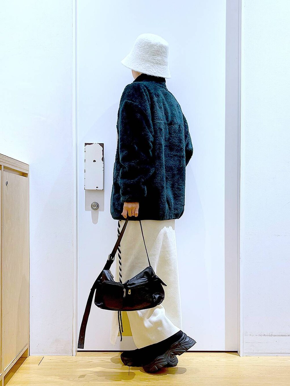 ブラック系のブーツ、ベージュ系のスカート、ブラック系のショルダーバッグを着用したレディースの冬コーディネートの3枚目の写真