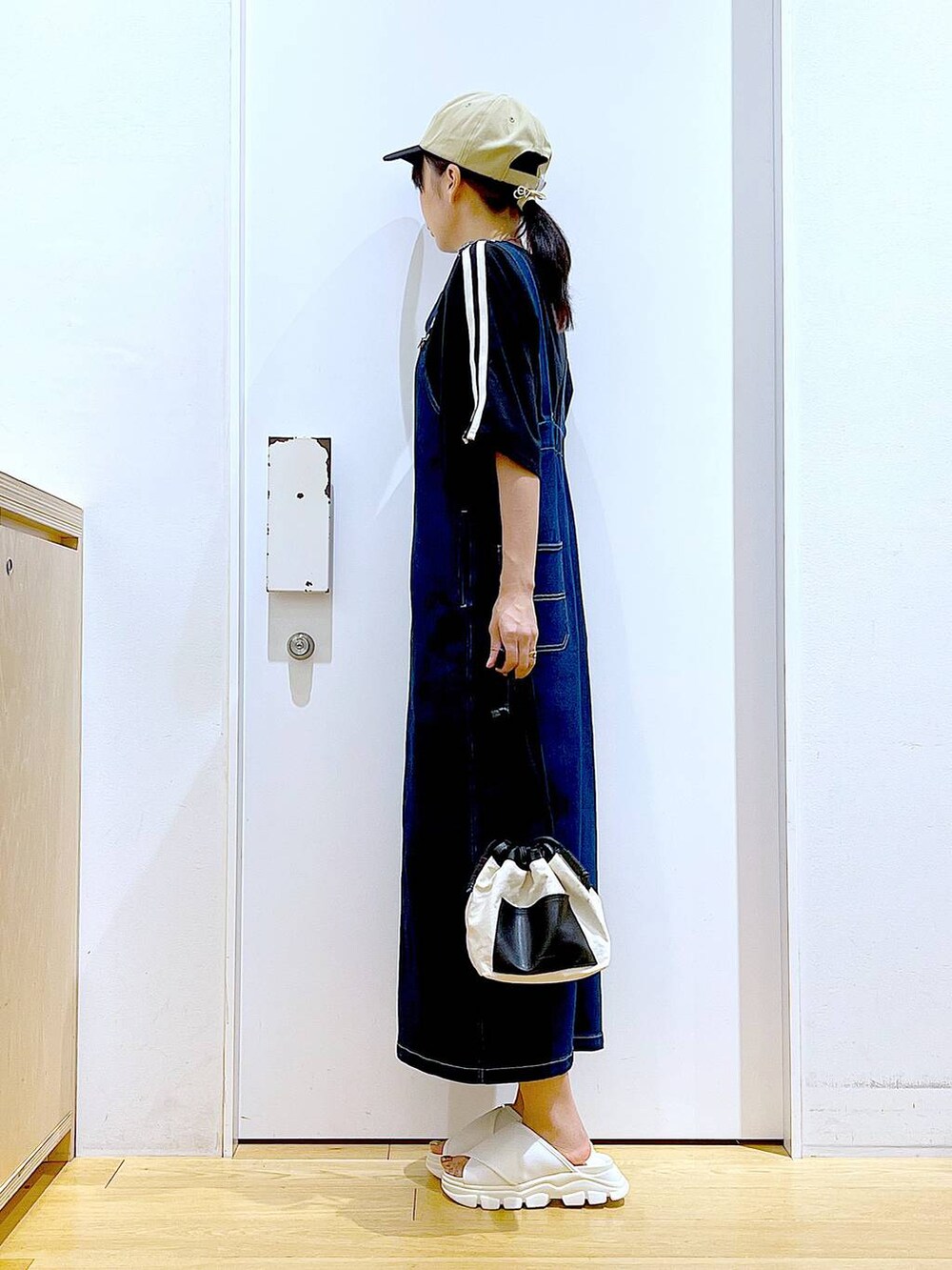 ブルー系のジャンパースカート、ホワイト系のショルダーバッグ、ホワイト系のサンダルを着用したレディースの夏コーディネートの3枚目の写真