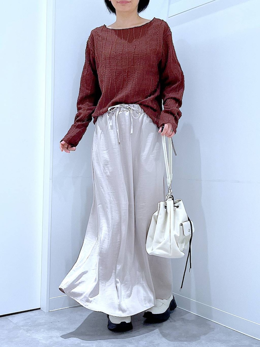 ホワイト系のローファー、ホワイト系のショルダーバッグ、ベージュ系のスカートを着用したレディースの秋コーディネートの6枚目の写真