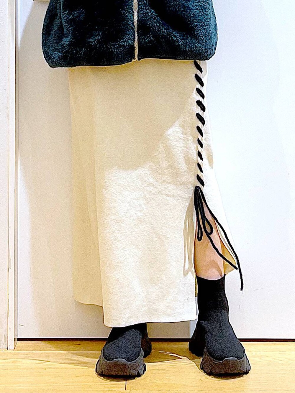 ブラック系のブーツ、ベージュ系のスカート、ブラック系のショルダーバッグを着用したレディースの冬コーディネートの8枚目の写真