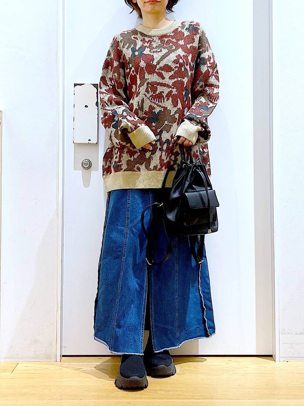 ブラック系のバックパック/リュック、ブルー系のデニムスカート、ブラック系のブーツを着用したレディースの冬コーディネートの6枚目の写真