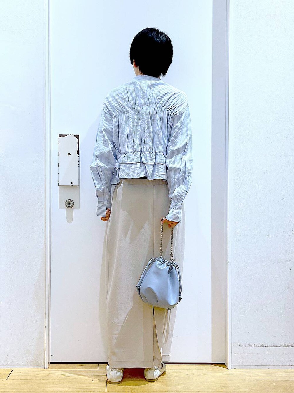 ブルー系のショルダーバッグ、ホワイト系のパンプス、ベージュ系のスカートを着用したレディースの春コーディネートの5枚目の写真