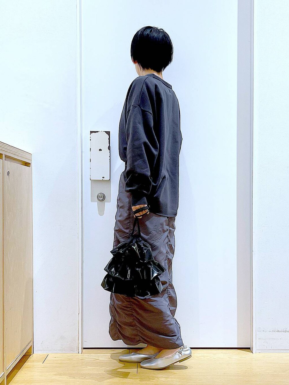 グレー系のスカート、ブラック系のショルダーバッグ、シルバー系のパンプスを着用したレディースの春コーディネートの3枚目の写真