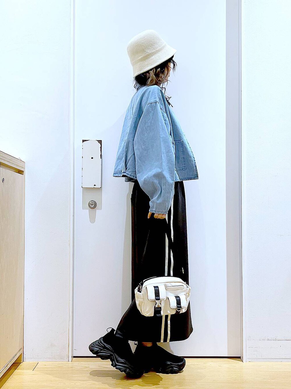 ブルー系のデニムジャケット、ブラック系のスカート、ブラック系のスニーカーを着用したレディースの春コーディネートの4枚目の写真