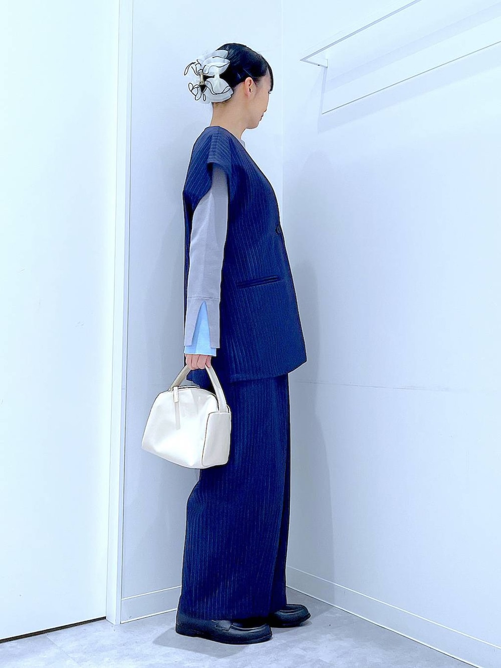 ホワイト系のショルダーバッグ、ブルー系のスラックス、ブルー系のベストを着用したレディースの冬コーディネートの4枚目の写真