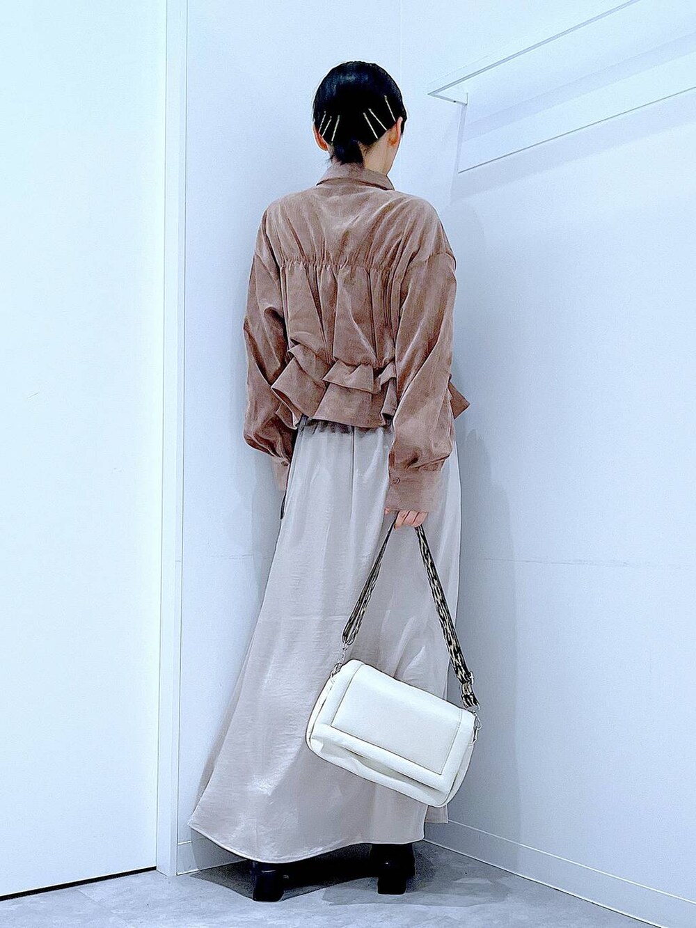 ベージュ系のスカート、ホワイト系のショルダーバッグ、ブラック系のブーツを着用したレディースの秋コーディネートの5枚目の写真