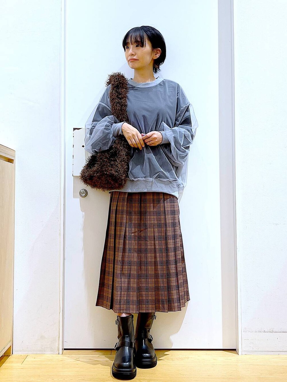 ブラック系のブーツ、ブラウン系のショルダーバッグ、ブラウン系のスカートを着用したレディースの秋コーディネートの2枚目の写真