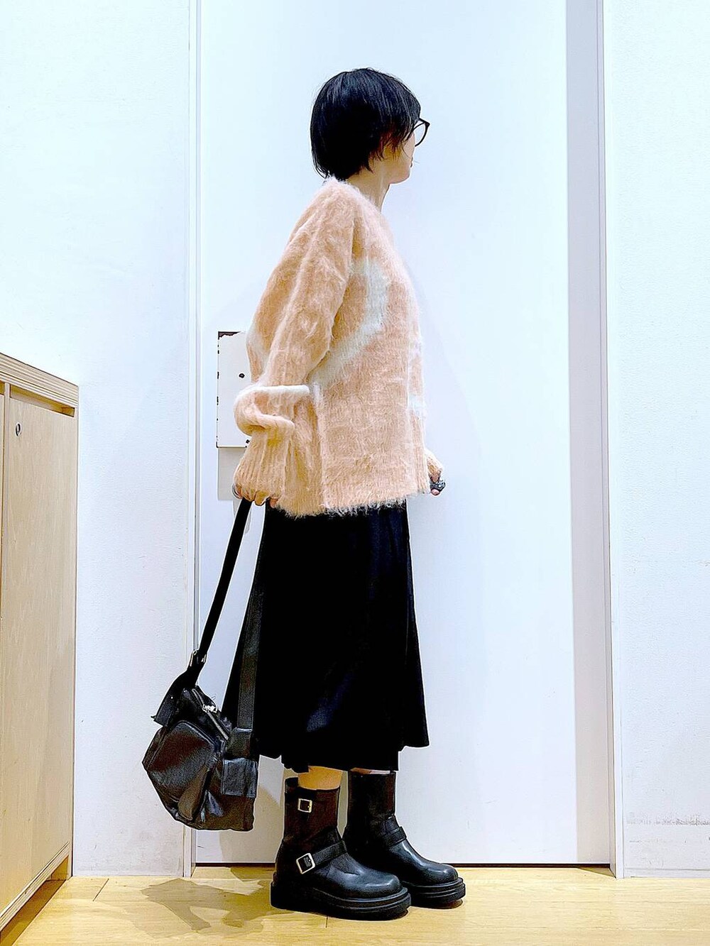 ピンク系のニット/セーター、ブラック系のブーツ、ブラック系のショルダーバッグを着用したレディースの秋コーディネートの4枚目の写真