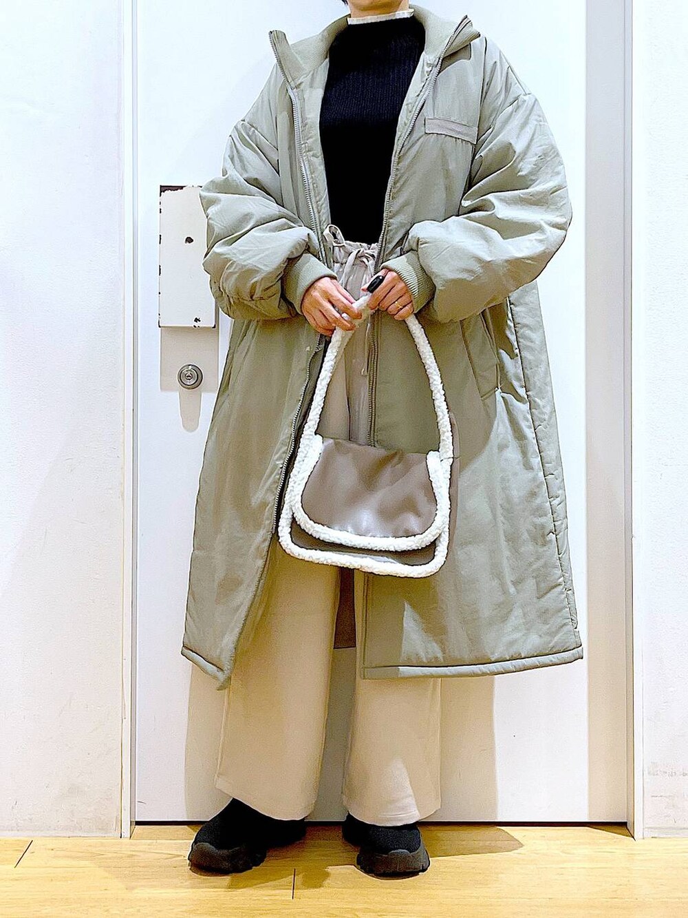 ブラック系のニット/セーター、ベージュ系のショルダーバッグ、ブラック系のブーツを着用したレディースの冬コーディネートの6枚目の写真