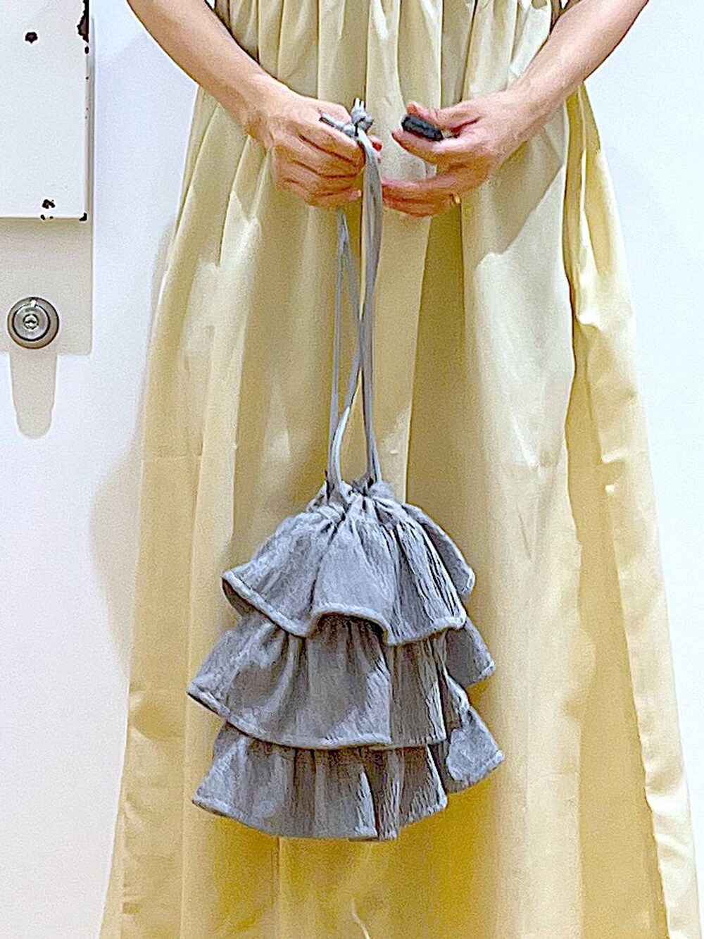 ブラック系のサンダル、イエロー系のワンピース、ブラック系のカーディガン/ボレロを着用したレディースの夏コーディネートの9枚目の写真