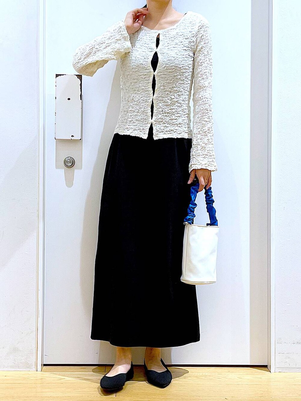 ブルー系のショルダーバッグ、ブラック系のパンプス、ブラック系のワンピースを着用したレディースの春コーディネートの6枚目の写真