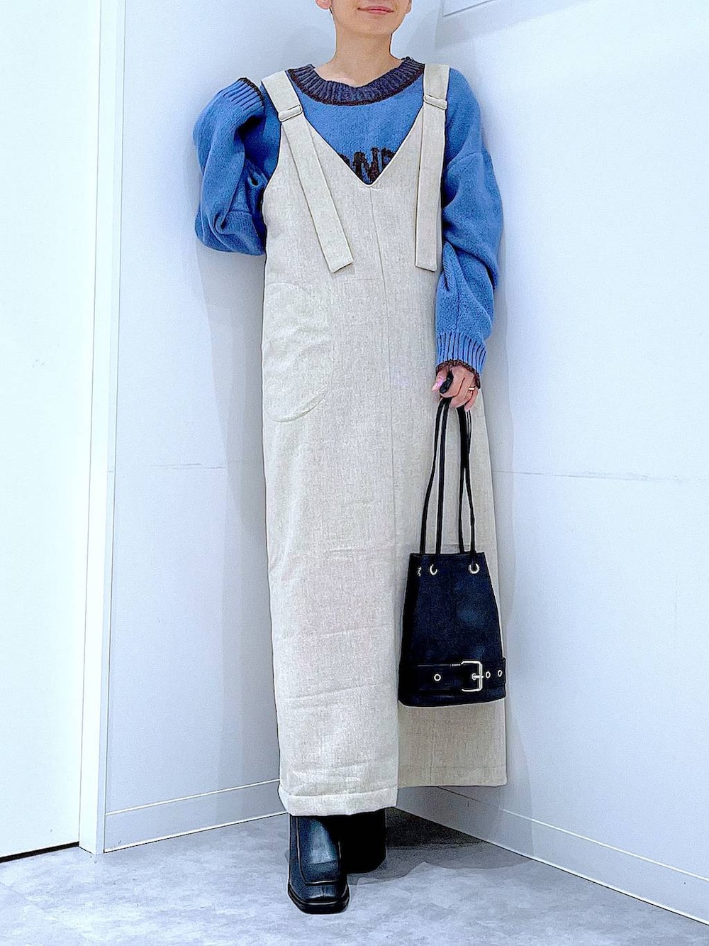 ブラック系のブーツ、ブラック系のハンドバッグ、ブルー系のニット/セーターを着用したレディースの秋コーディネートの6枚目の写真