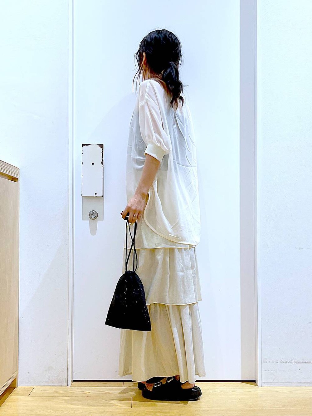 ブラック系のサンダル、ブラック系のショルダーバッグ、ゴールド系のスカートを着用したレディースの夏コーディネートの3枚目の写真