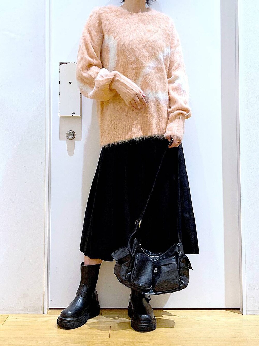 ピンク系のニット/セーター、ブラック系のブーツ、ブラック系のショルダーバッグを着用したレディースの秋コーディネートの6枚目の写真