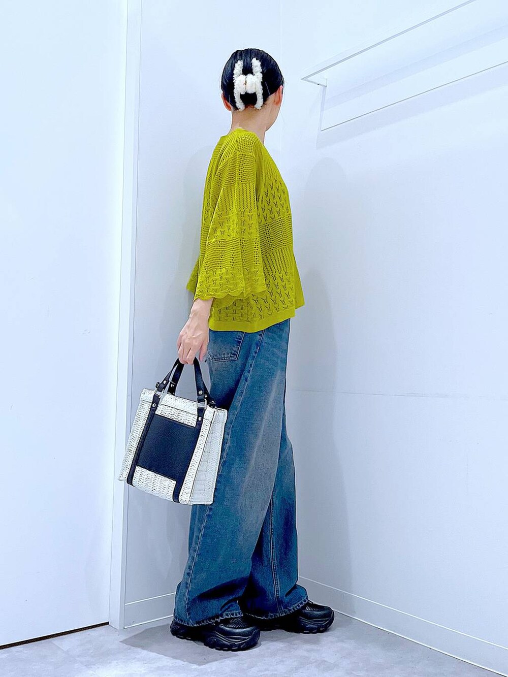 ブルー系のデニムパンツ、ブラック系のスニーカー、ホワイト系のショルダーバッグを着用したレディースの春コーディネートの4枚目の写真