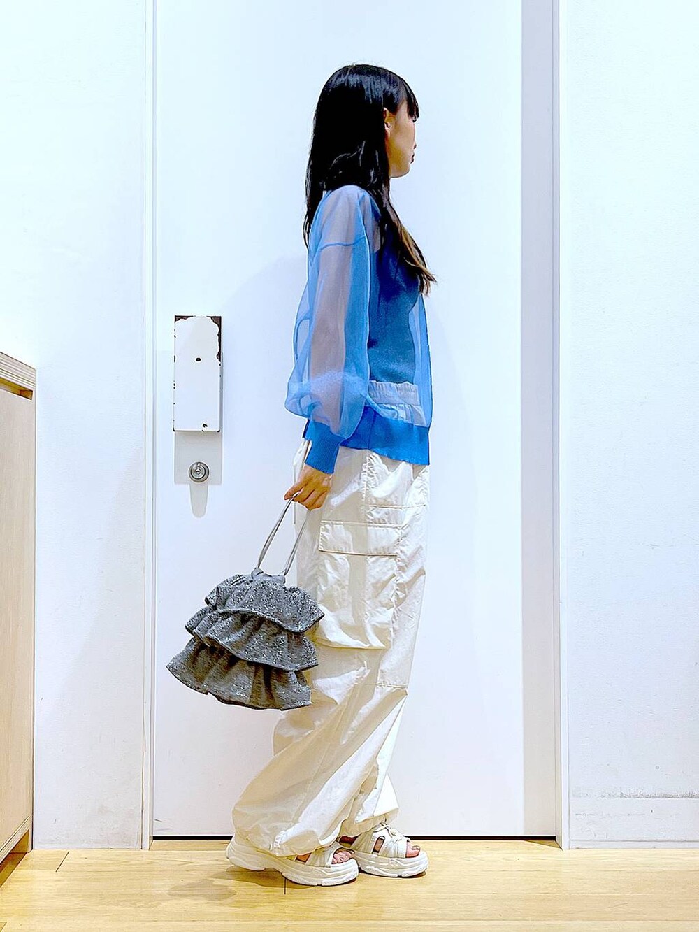 シルバー系のショルダーバッグ、ホワイト系のカーゴパンツ、ブラック系のニット/セーターを着用したレディースの夏コーディネートの4枚目の写真