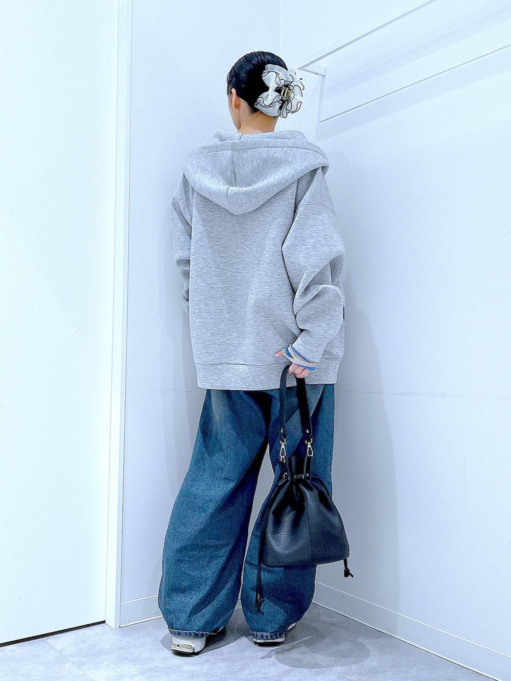 ブルー系のデニムパンツ、グレー系のパーカー、ブラック系のショルダーバッグを着用したレディースの冬コーディネートの5枚目の写真