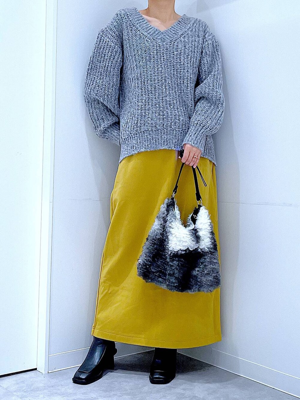 グレー系のニット/セーター、イエロー系のスカート、ブラック系のブーツを着用したレディースの冬コーディネートの6枚目の写真