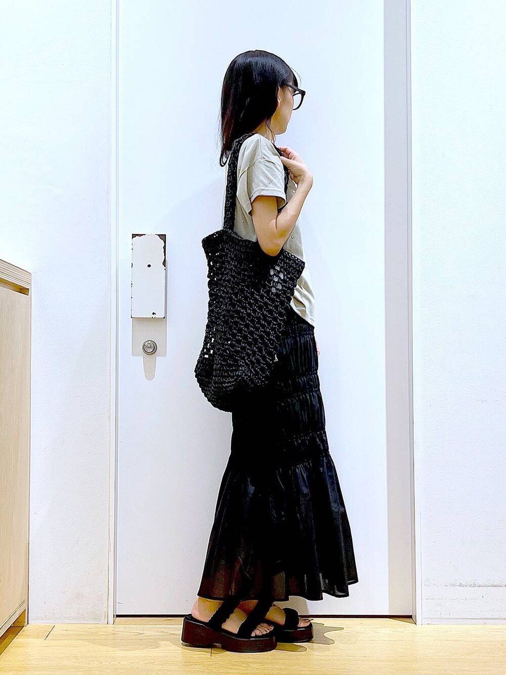 ブラック系のサンダル、ブラック系のスカート、ブラック系のトートバッグを着用したレディースの夏コーディネートの4枚目の写真