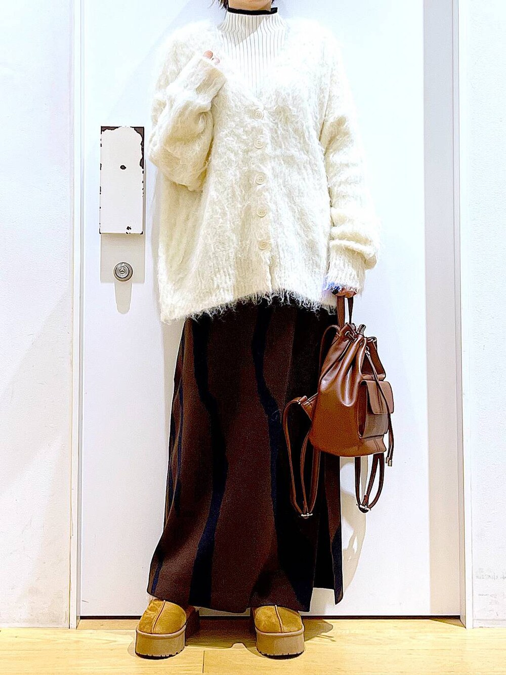 ベージュ系のニット/セーター、ブラウン系のバックパック/リュック、ブラウン系のスカートを着用したレディースの冬コーディネートの6枚目の写真