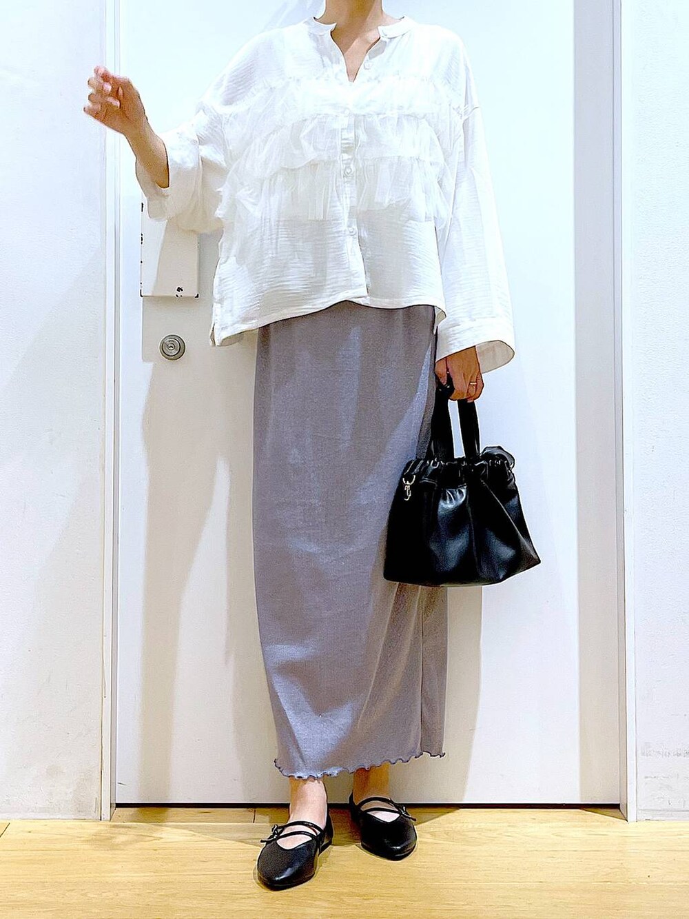 パープル系のスカート、ブラック系のショルダーバッグ、ブラック系のパンプスを着用したレディースの秋コーディネートの6枚目の写真