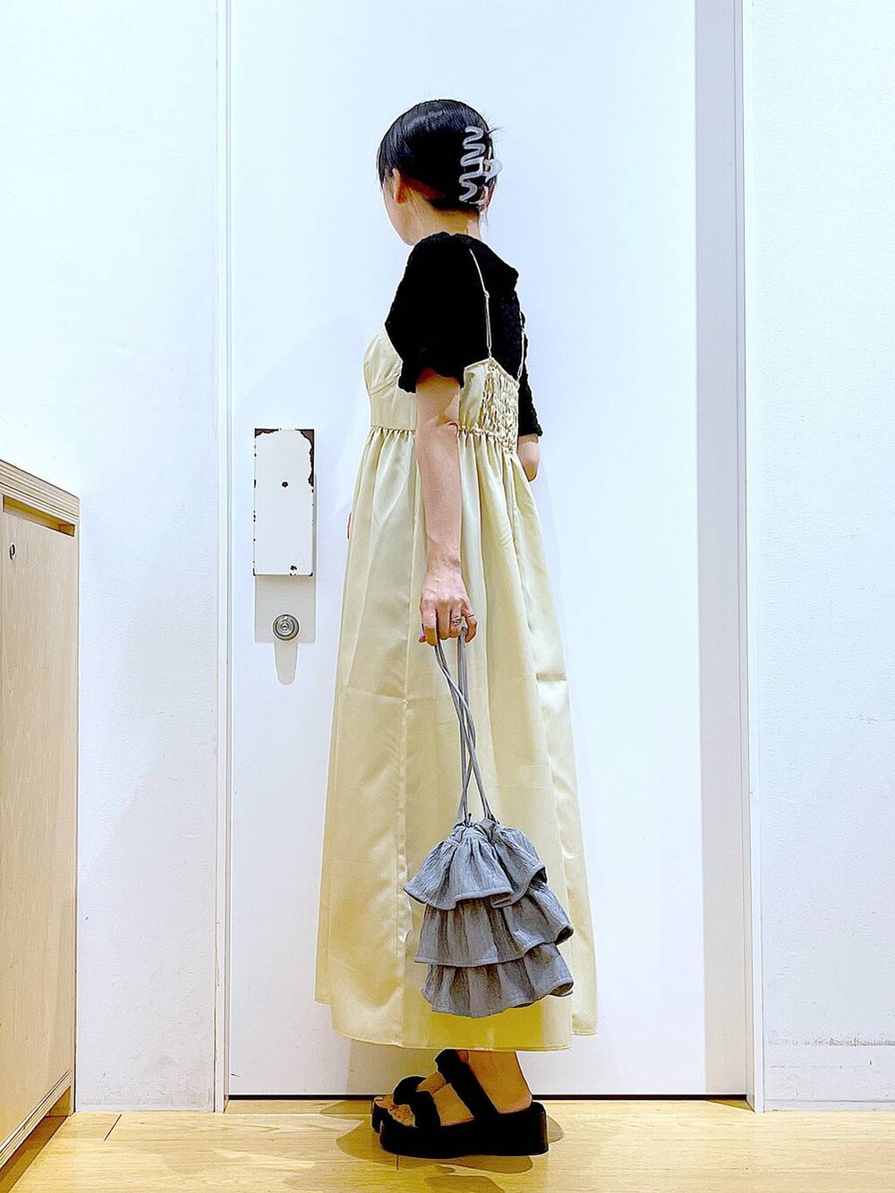 ブラック系のサンダル、イエロー系のワンピース、ブラック系のカーディガン/ボレロを着用したレディースの夏コーディネートの3枚目の写真